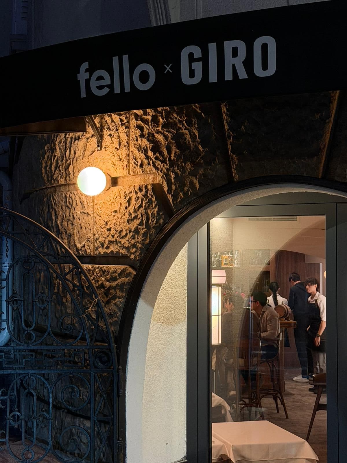 Ulaz restorana fello x GIRO noću, sa natpisom i osvetljenim lukom