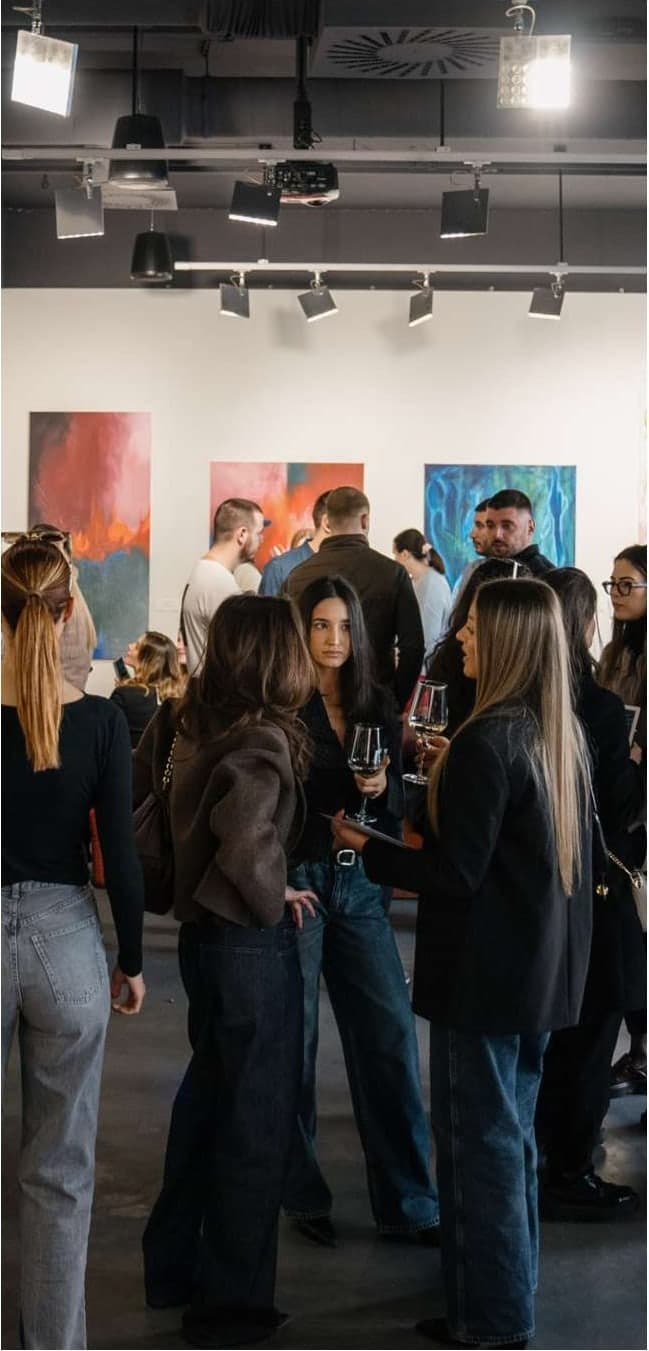 Posetioci ispred tri slike na otvaranju izložbe