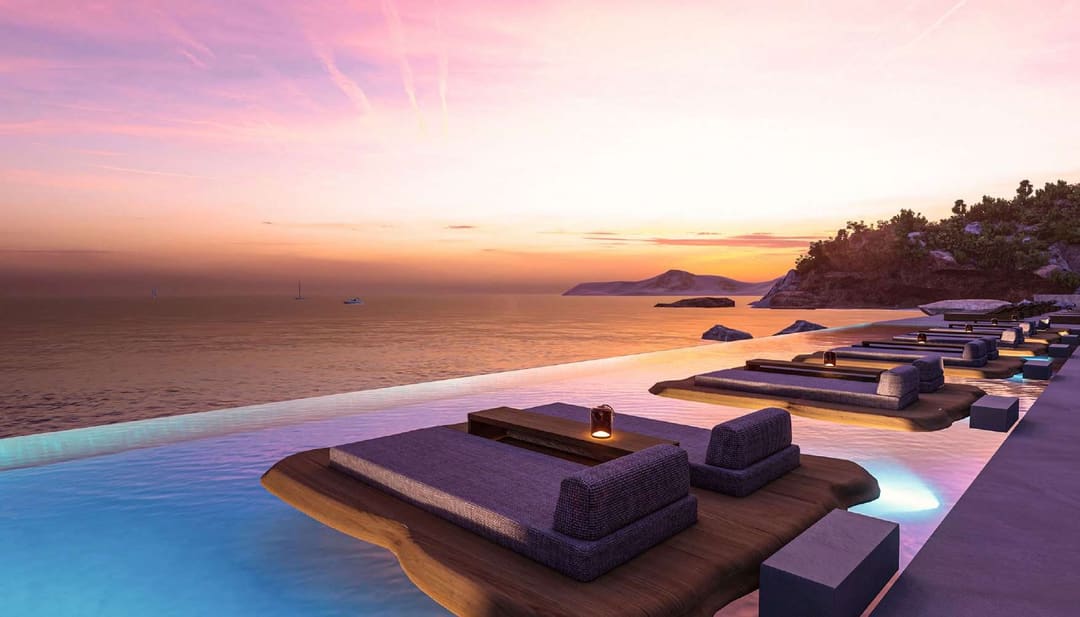 Loungers on platforms by a pool overlooking the sea at sunset