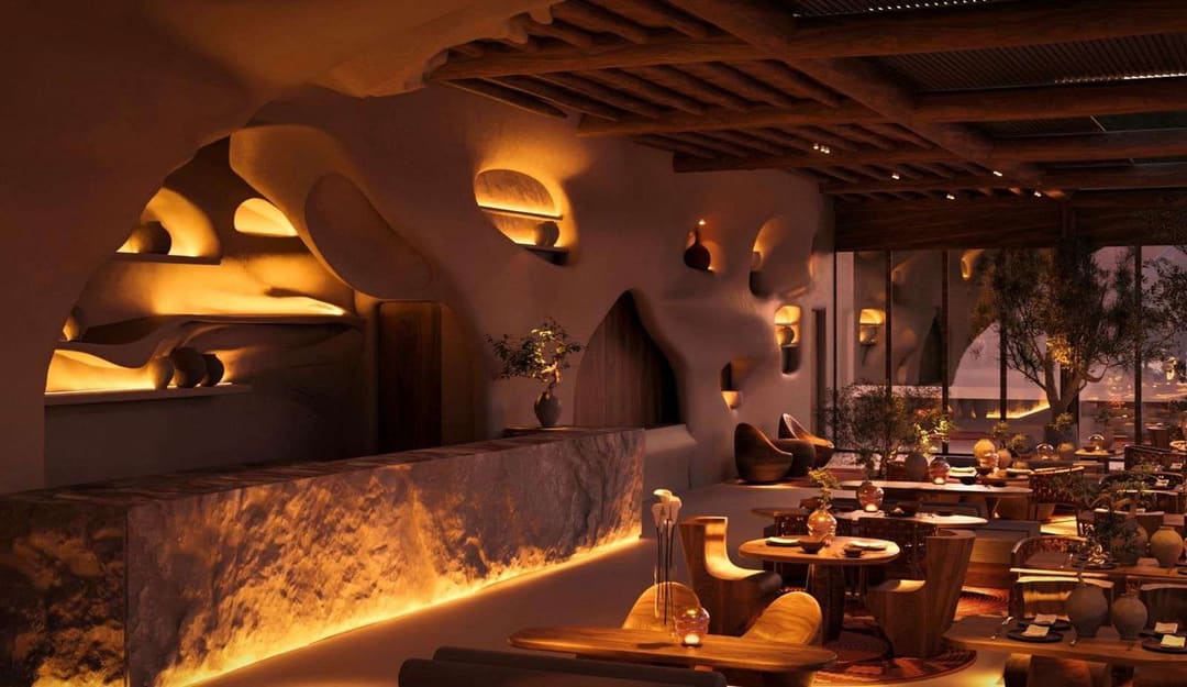 Restaurant with organic walls, warm light and a stone bar